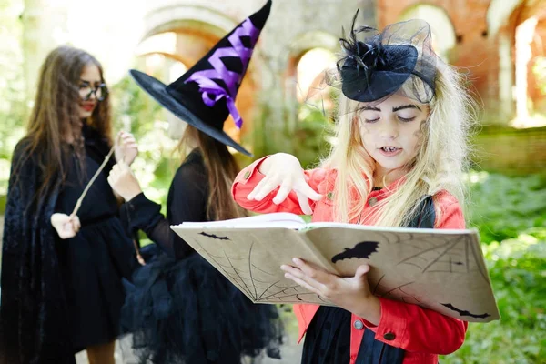 Cute Girl Halloween Attire Looking Spell Book Choosing Magic Spell — Stock Photo, Image