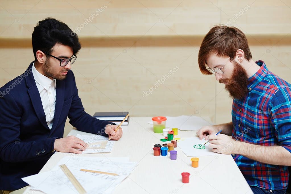 War of logic vs creativity: concentrated office worker in suit wrapped up in drawing architecture project with pencil and ruler while other man in casualwear creating picture with brush and gouache
