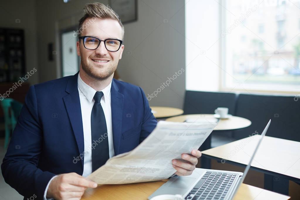 Job seeker with newspaper and laptop looking for vacancies