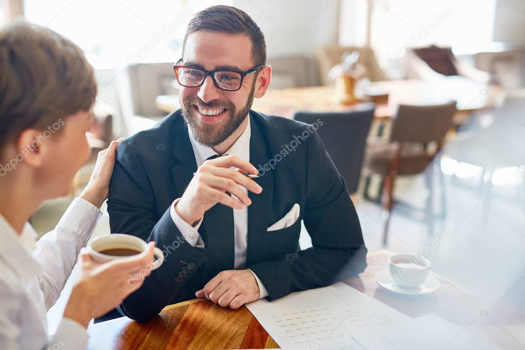 Smiling business leader and his partner having talk by cup of tea