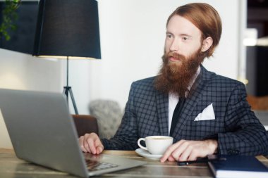 Kafede kahve sahip ve dizüstü online video izlerken sakallı analisti