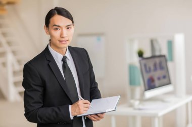 İş planı veya proje noktaları not defterinde yazılı takım elbiseli genç adam