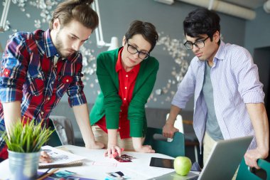 Grup ofis toplantıda masa daimi işbirliği ve fotoğraf ve belgeleri bakarak rahat kıyafetler giymiş genç yaratıcı insan