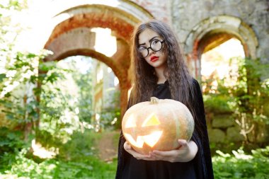 Küçük kız siyah büyücü ve Cadılar Bayramı Balkabağı tutan gözlük