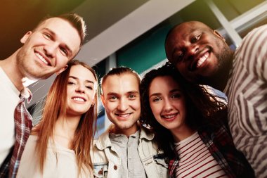 Poz fotoğraf panoramik pencerelere, bel-up grup portre karşı dururken için neşeli arkadaşları düşük açılı görünüş