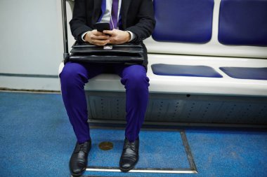 Tanınmayan işadamı smartphone kullanarak ve kulaklık müzik metro tren oturan orta bölüm çekim