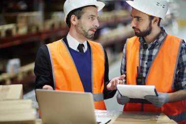 Depo yöneticisi yükleyici için malların listesini uymak için dizüstü bilgisayar kullanarak stocktaking yaparken söz portresi