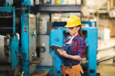 Koruyucu gözlük ve makine ve dijital tablet yardımı ile not almak inceleme hardhat oldukça genç teknisyen