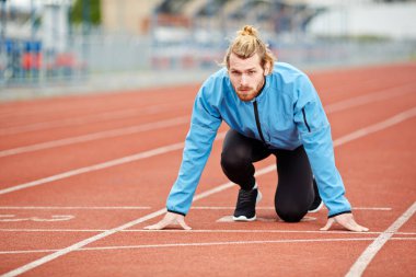 Genç atlet atletizm Stadyumu çalıştırmak için hazırlanıyor, başlangıç çizgisi üzerinde belirlenen