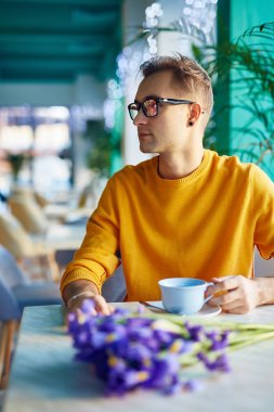 Süsen buket Tarih için bekleyen kafede romantik genç adam portresi