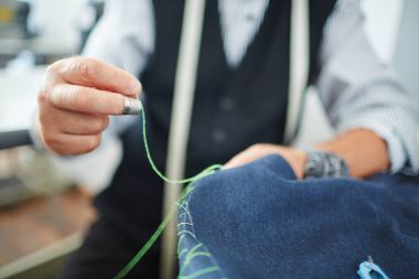 İş sırasında parmağında yüksük olan terzi eli.