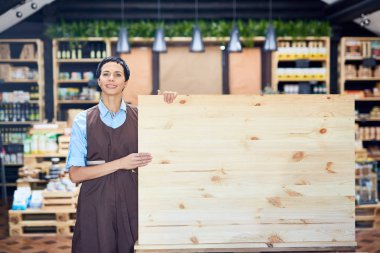 Oldukça orta yaşlı tezgâhtar holding boş ahşap yönetim kurulu duran güzel mağaza organik ürünlerle portre vurdu önlük