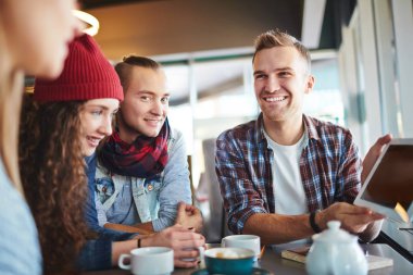 Kafeterya masada oturan ve dijital tablet ile istatistik veri meslektaşları için gösterilen yakışıklı genç Yöneticisi portresi