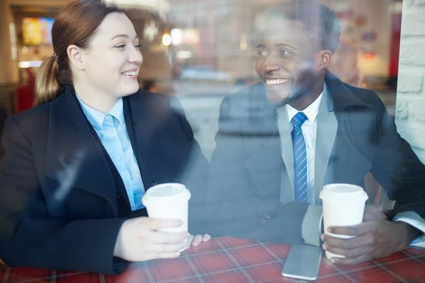 两位商界人士在咖啡馆工作后相遇 英俊的非洲裔美国商人看着他的女同事微笑着聊天 都穿着大衣 — 图库照片