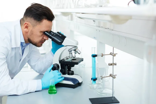 在实验室从事重要医学研究发明药物时用显微镜观察帅科学家的肖像 — 图库照片