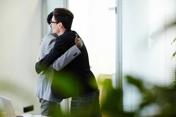 年轻的同事拥抱对方作为问候或祝贺 — 图库照片