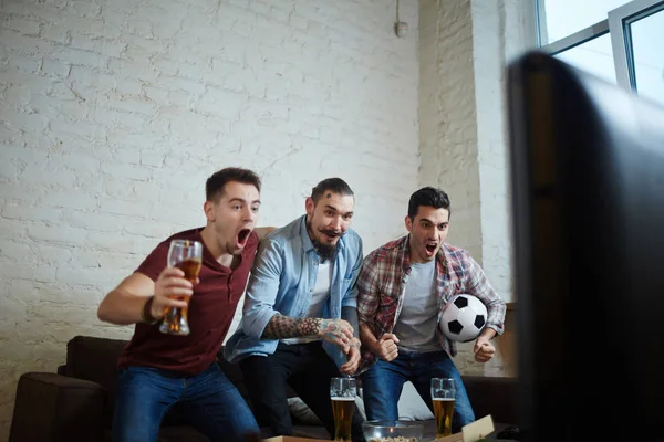 在电视上观看体育比赛的三情绪化成年男子的画像和兴奋的欢呼 而站起来 并与啤酒尖叫 — 图库照片