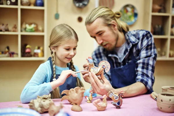 Young Man Showing His Daughter How Paint Clay Toys — Stock Photo, Image