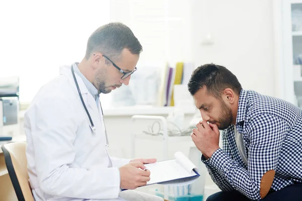 Kranker Mann Sitzt Arzt Nach Ärztlicher Untersuchung Gegenüber Und Macht — Stockfoto