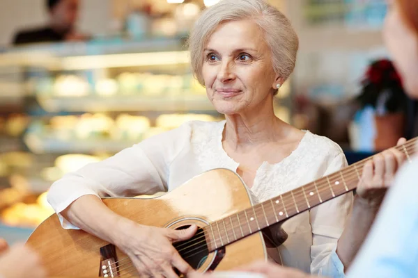高齢者女性のレジャーでギターを弾く — ストック写真