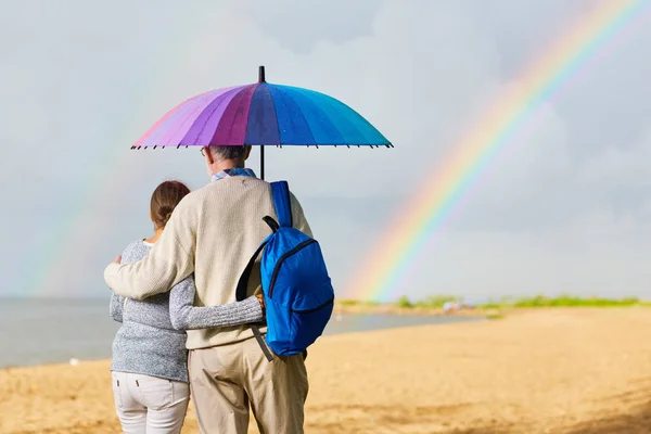 Embracing Seniors Umbrella Walking Beach — Stock Photo, Image