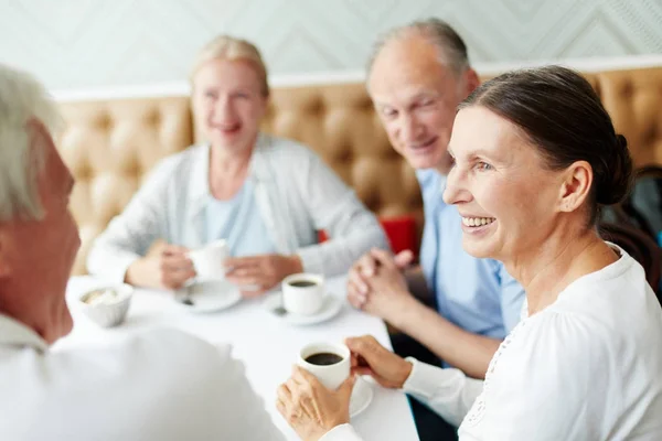 一组高级同伴坐在咖啡馆的餐桌旁 喝杯咖啡聊天 — 图库照片