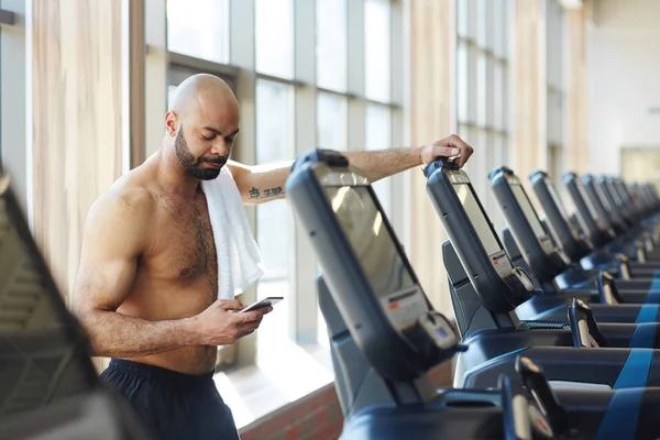 Junger Sportlicher Mann Stützt Sich Auf Laufband Und Sms Smartphone — Stockfoto