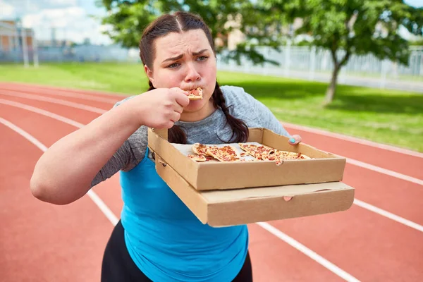 Plump Female Eating Takeout Pizza Box While Walking Racetrack — Stock Photo, Image