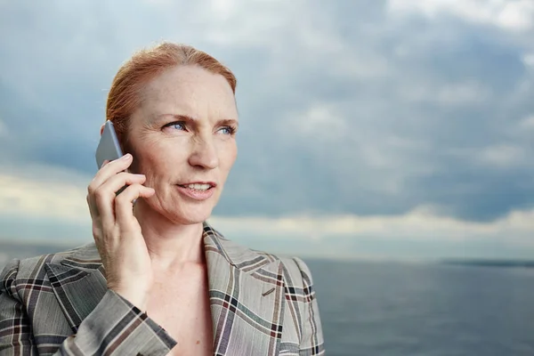 Bossy woman speaking by smartphone on stormy weather