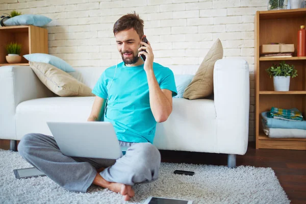 Jovem Positivo Com Barba Falando Telefone Quando Ele Usa Laptop — Fotografia de Stock