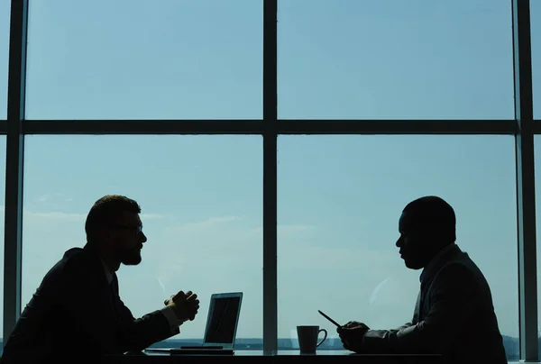 两位自信的商业伙伴在现代昏暗的会议室里坐在一起进行谈判的剖面图 — 图库照片