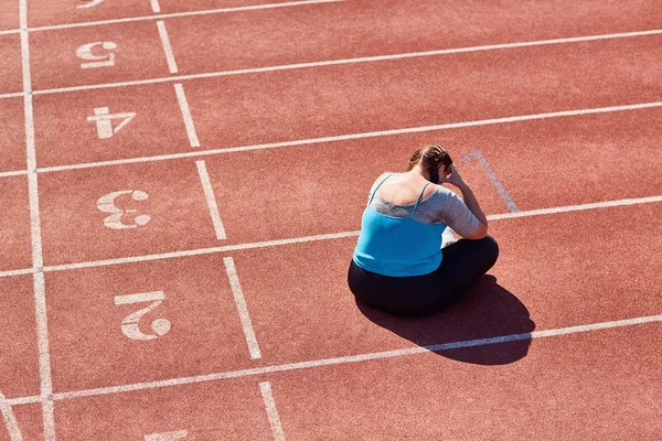 失意的大女子坐在跑道上 在训练后哭泣 — 图库照片