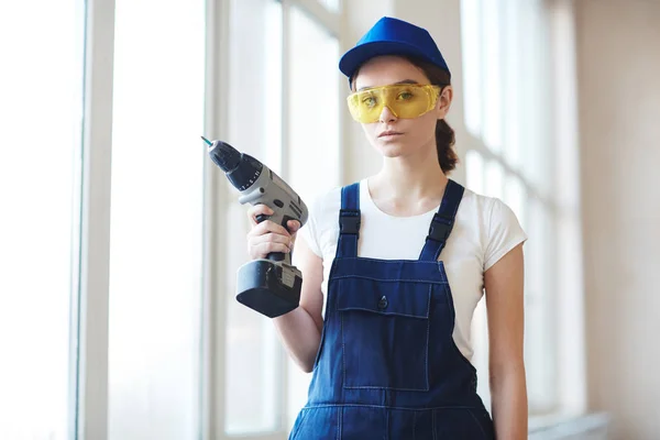 年轻自信的妇女的画像工作与电钻在建筑工地上安装窗户 — 图库照片