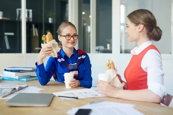 サンドイッチを食べ デスクで雑談して可愛い女の子 — ストック写真