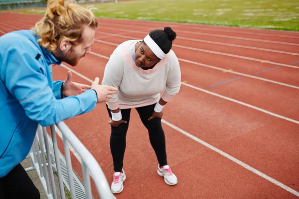 若いスポーティなプラス サイズ女の子スタジアムでトレーニング中に彼女のトレーナーのアドバイスを聞いて — ストック写真