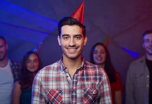英俊的家伙在生日帽和他的朋友在背景 — 图库照片