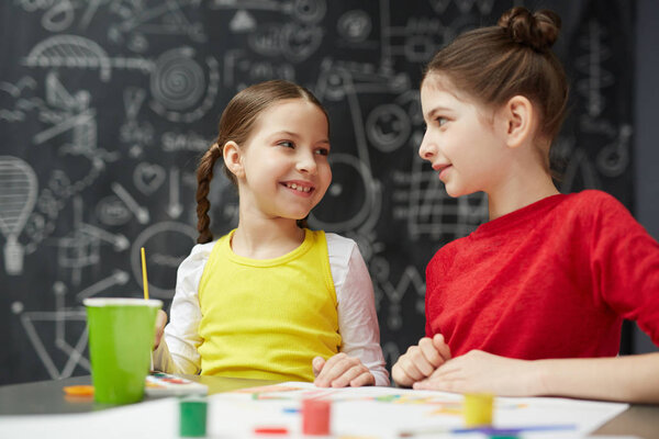 Schoolgirls discussing ideas of drawing