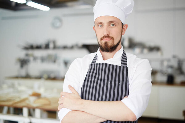 Bearded baker in uniform looking at camera