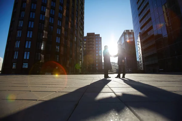 それらは レンズのフレアを照らす夕日の最後はりの屋外で立ちながらしっかり握手 つの認識できないビジネスマンの低角度のビュー — ストック写真