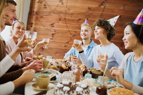 愉快的朋友与饮料做敬酒在生日桌和享受党 — 图库照片