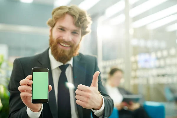 スマート フォンで新しいアプリを見せながら幸せな男を示す親指アップ — ストック写真