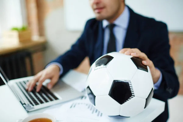 ビジネスマンのオフィスでラップトップ上で入力の職場にはサッカー ボール — ストック写真