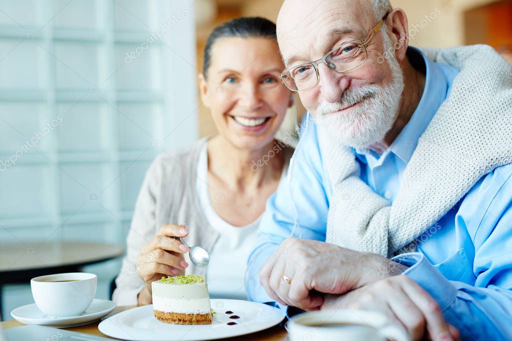 Happy senior man and his wife eating dessert in cafe