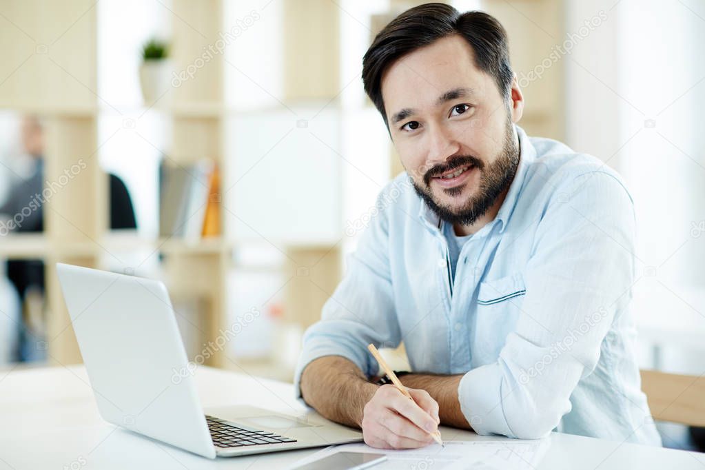 Contemporary economist sitting by workplace and planning working day