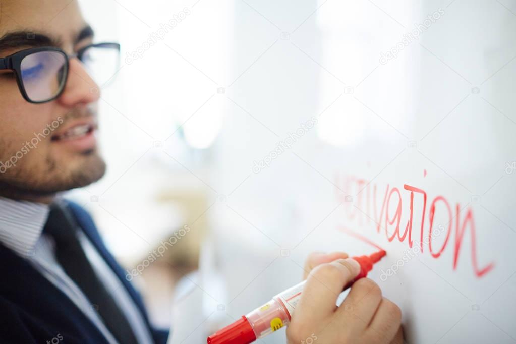 Businessman underlining word motivation written on whiteboard with red highlighter