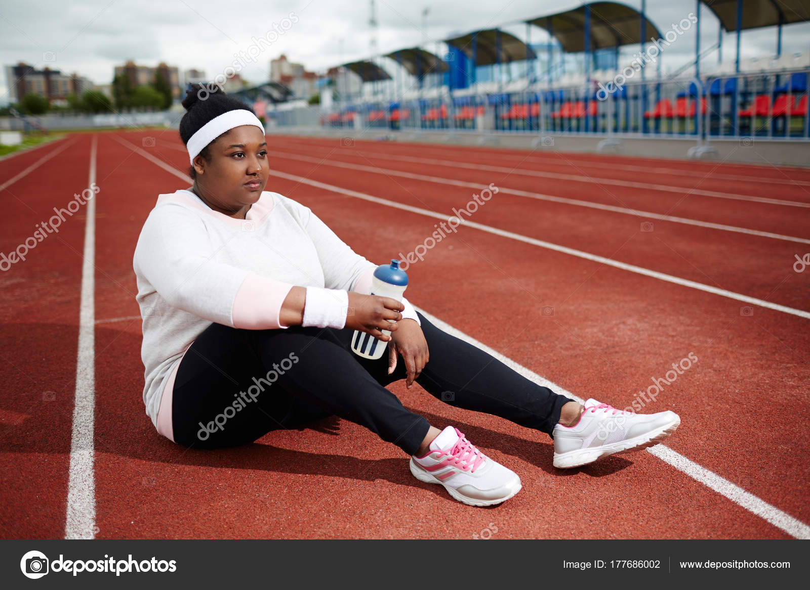 Femme Africaine Surpoids Dans Les Vetements Sport Assis Sur Piste Photo de stock par pressmaster 177686002