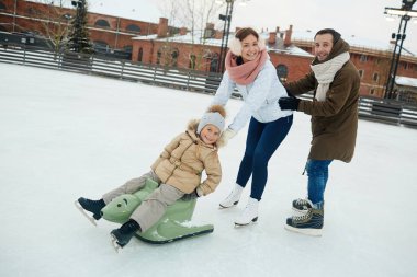 Üç eğleniyor buz pateni pisti üzerinde kış gününde neşeli aile
