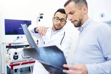 İki adam, ragiologist ve hasta randevu sırasında x-ışını görüntüleri seyir,