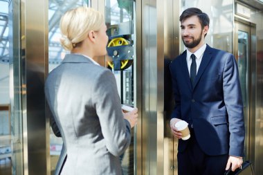 İki iş arkadaşları, erkek ve kadın, modern ofis binası asansörde sohbet portresi