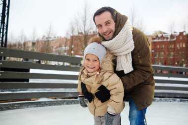 Mutlu bir adam ve küçük kızı buz pateni pisti üzerinde boş zaman zevk